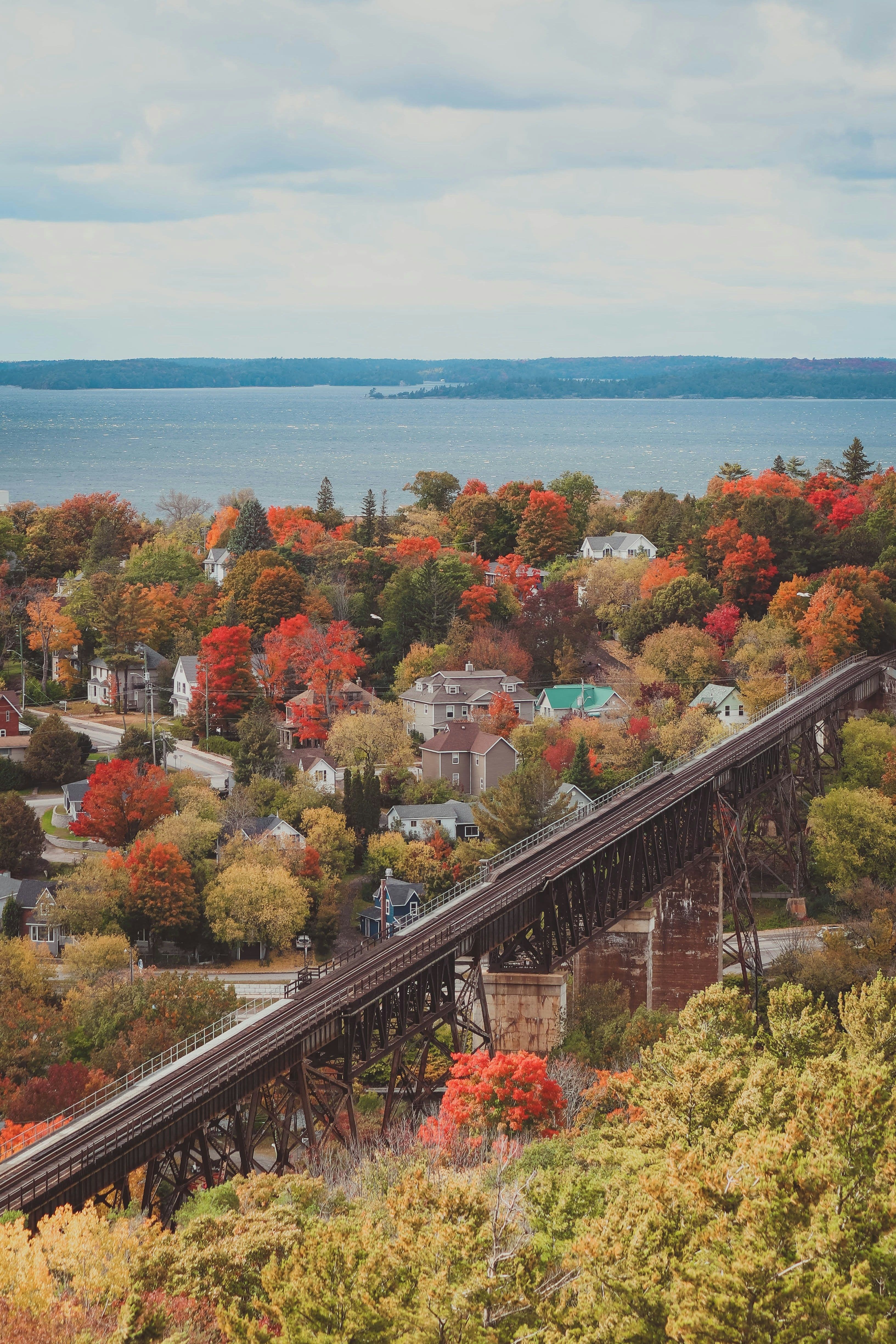 Railway trestle bridge over a calm northern river framed by autumn trees in Parry Sound, Ontario