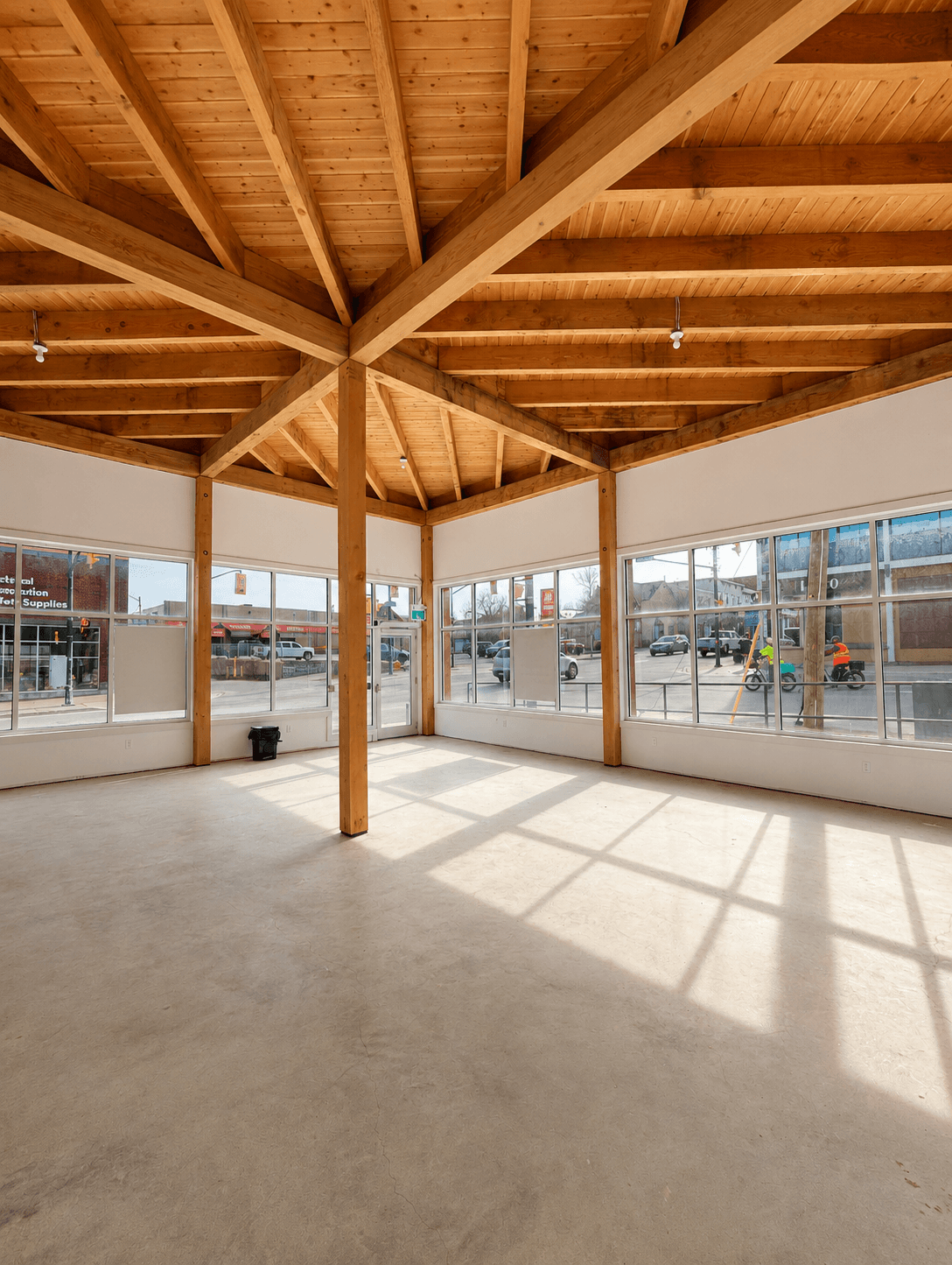 A bright open retail space with timber-frame ceilings and large street-facing windows in downtown Parry Sound.